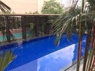 Swimming pool area with greenery and buildings in background