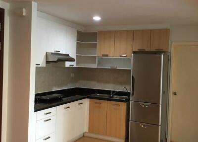 Modern kitchen with white and wood cabinetry, black countertops, and stainless steel appliances