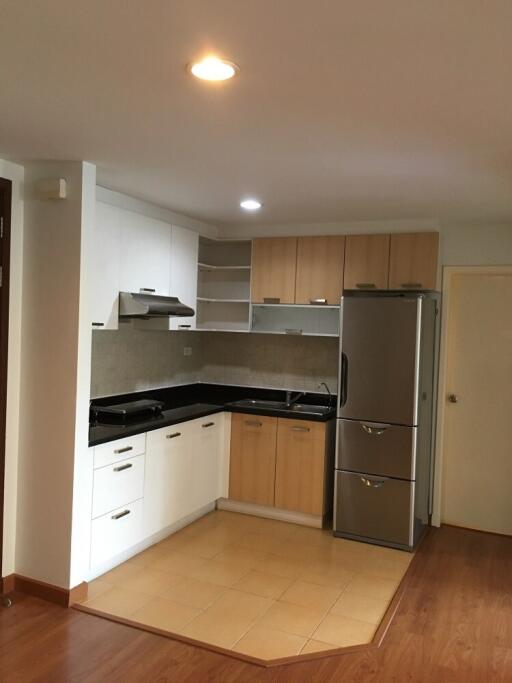 Modern kitchen with white and wood cabinetry, black countertops, and stainless steel appliances