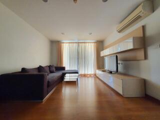 Living room with sofa, television, and air conditioning unit