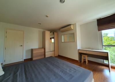 Spacious bedroom with hardwood floors, large window, and modern furnishings.