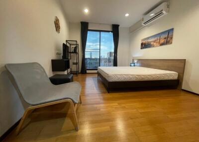 Spacious bedroom with hardwood floors, large bed, and city view from the window