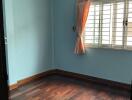 Empty bedroom with wooden floor and blue walls