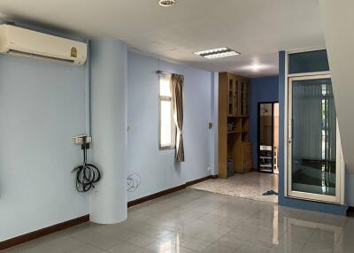 Main living area with light blue walls, large windows, air conditioning unit, and tiled floor