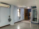 Main living area with light blue walls, large windows, air conditioning unit, and tiled floor