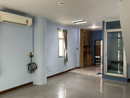 Main living area with light blue walls, large windows, air conditioning unit, and tiled floor