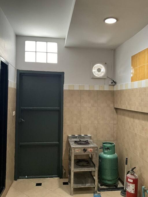 Photo of a kitchen with a stove, gas cylinder, and fire extinguisher