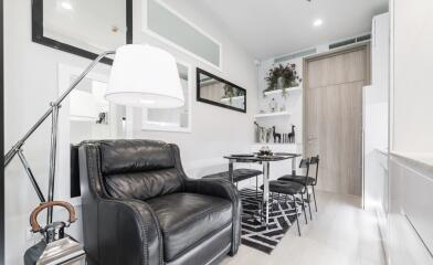 Modern living room with lamp, leather chair, dining table and wall-mounted decorations