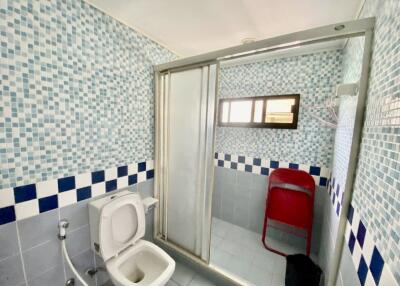 Bathroom with tiled walls, shower, and toilet