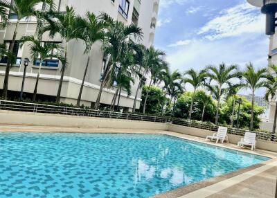 Outdoor swimming pool with palm trees and lounge chairs