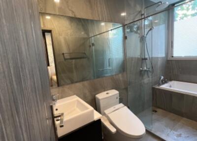 Modern bathroom with glass shower, toilet, sink, and bathtub