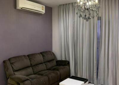 Living room with a brown sofa, modern coffee table, air conditioner, chandelier, and light curtains