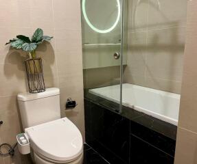 Modern bathroom with toilet, bathtub, and plant