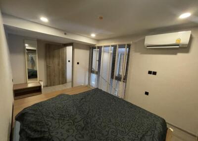 well-lit bedroom with a bed, air conditioner, and mirrored wardrobe