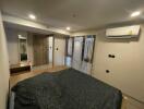 well-lit bedroom with a bed, air conditioner, and mirrored wardrobe