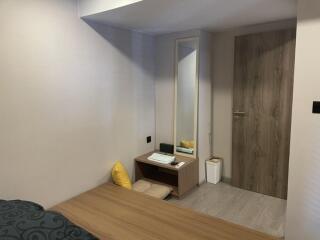 Bedroom with a wooden desk, mirror, and door