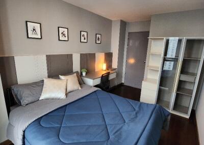 A modern bedroom with a neatly made bed, wall-mounted pictures, and contemporary furniture.