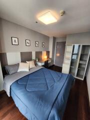 A modern bedroom with a neatly made bed, wall-mounted pictures, and contemporary furniture.