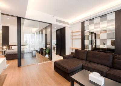 Modern living room with glass partition and adjacent bedroom