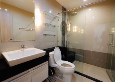 Modern bathroom with glass shower, sink, and toilet