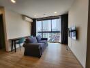 Modern living room with sofa, TV, and large windows