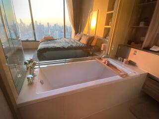 Modern bedroom with an attached bathroom featuring a bathtub and a city view.