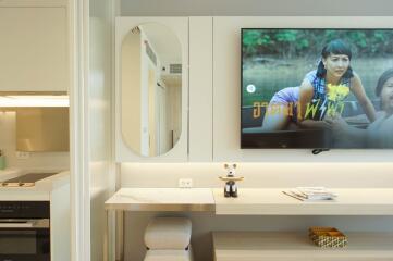 Modern living area with TV, kitchen unit, and wall-mounted desk