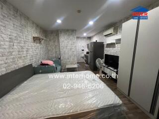 Bedroom with brick wall design, bed, sofa, and appliances