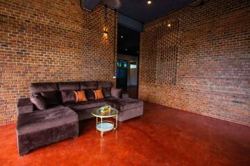 Spacious living room with a modern sofa against exposed brick walls