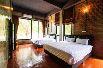 Bedroom with two large beds, exposed brick wall, and large windows