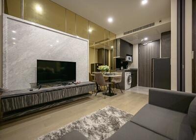 Modern living area with marble accent wall, flat-screen TV, and integrated kitchen in the background