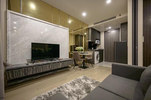 Modern living area with marble accent wall, flat-screen TV, and integrated kitchen in the background