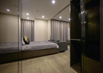 Modern bedroom with large bed, sofa, and ample lighting