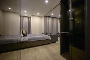 Modern bedroom with large bed, sofa, and ample lighting