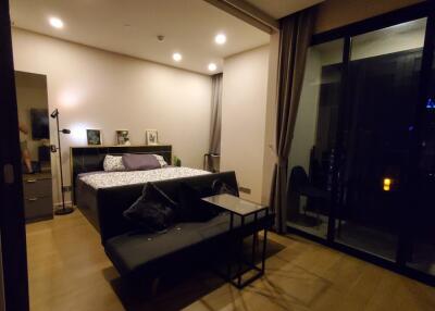 Bedroom with a large bed, nightstands, a sofa, and floor-to-ceiling windows.