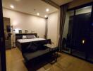 Bedroom with a large bed, nightstands, a sofa, and floor-to-ceiling windows.