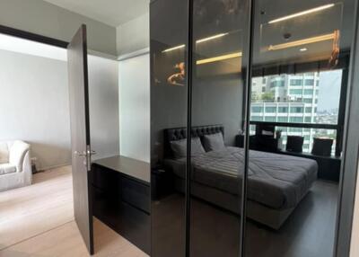 Modern bedroom with a large glass wardrobe, bed, and a view into the living area