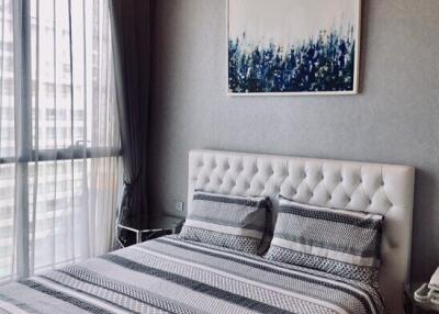 Modern bedroom with large window, artwork, and patterned bedding