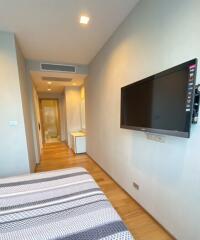 Modern bedroom with wooden flooring and wall-mounted TV