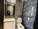 Modern bathroom with sleek design, featuring a toilet, vanity with sink, large mirror, and tiled walls