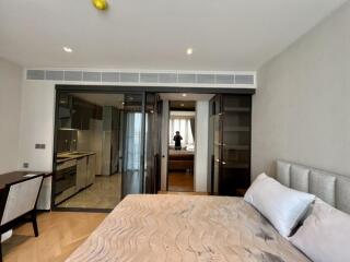 Modern bedroom with bed, desk, and view of kitchen through glass doors