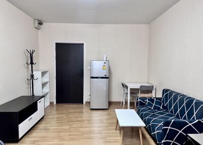 Main living area with sofa, TV stand, mini fridge, dining table, and coat rack