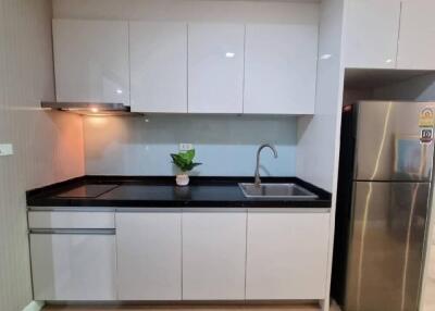 Modern kitchen with white cabinets, black countertop, and stainless steel appliances