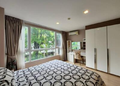 Spacious bedroom with large windows, bed, wardrobe, and workstation