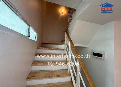 Staircase with wooden steps and wall-mounted handrail