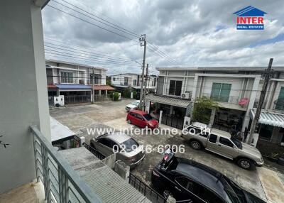 View from the front of the house, showing a residential street with houses, cars, and parking area