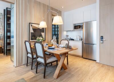 Modern dining area with wooden table and chairs next to a compact kitchen