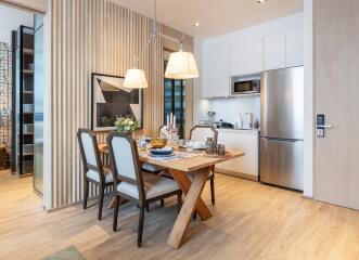 Modern dining area with wooden table and chairs next to a compact kitchen