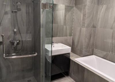 Modern bathroom with glass shower, bathtub, and sink