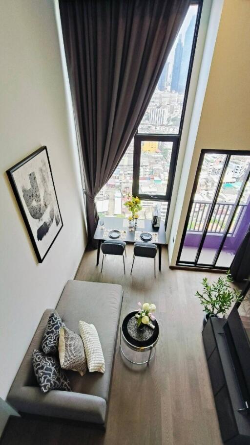 Well-decorated living room with a high ceiling and large windows